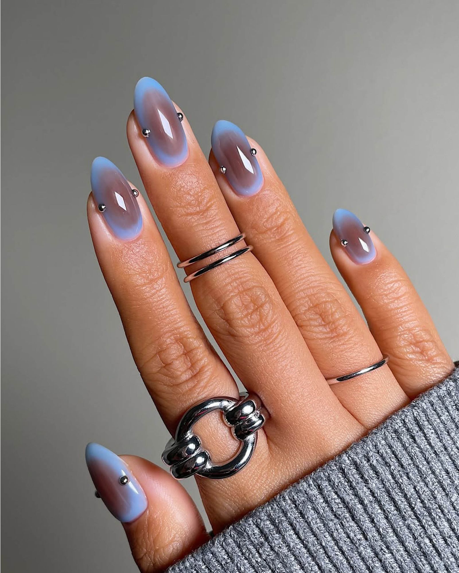 Light blue aura nails with mauve center and small silver balls on the sides.