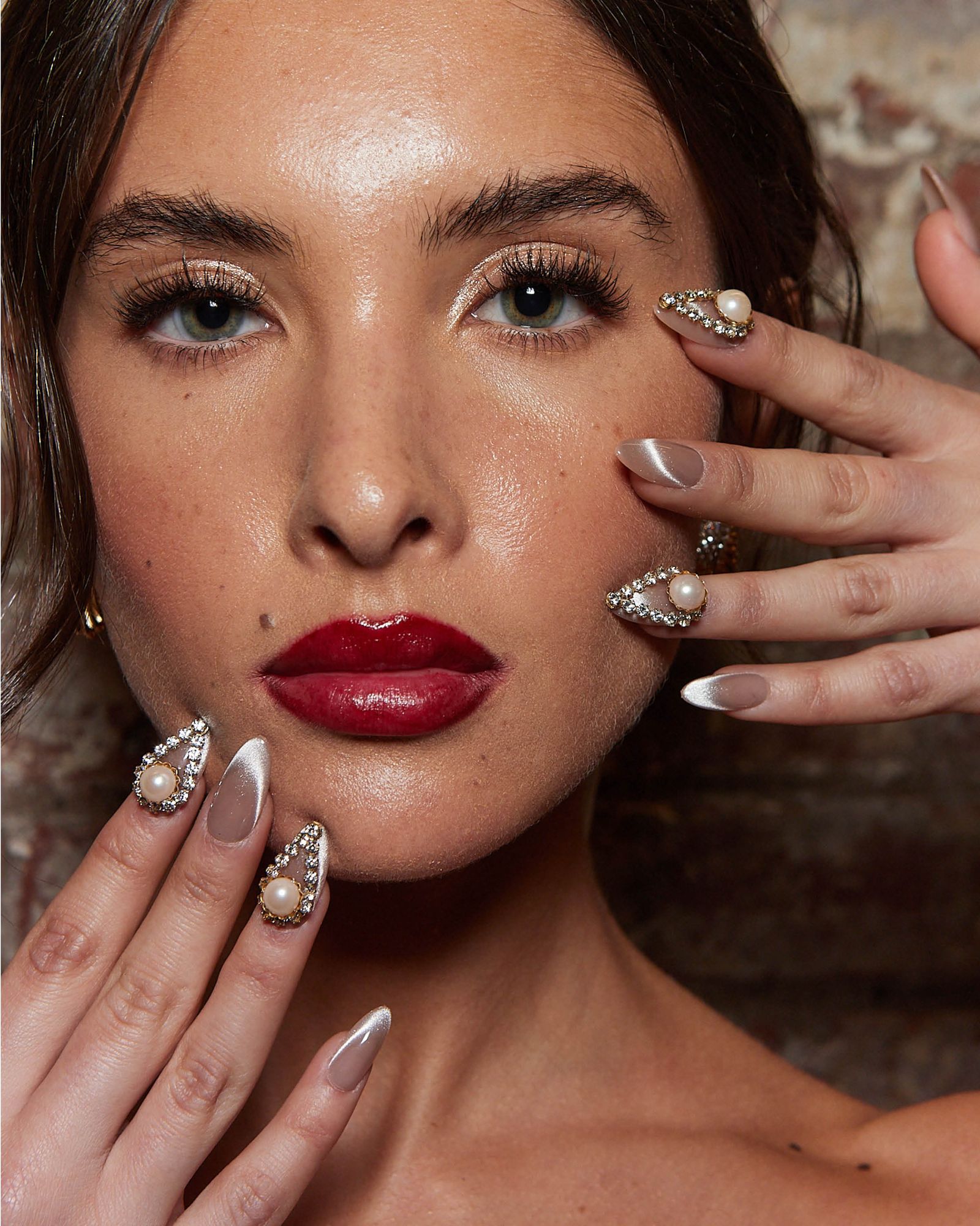 Nude shimmery nails with featured designs of gem stones in a tear drop shape encircling a large pearl.