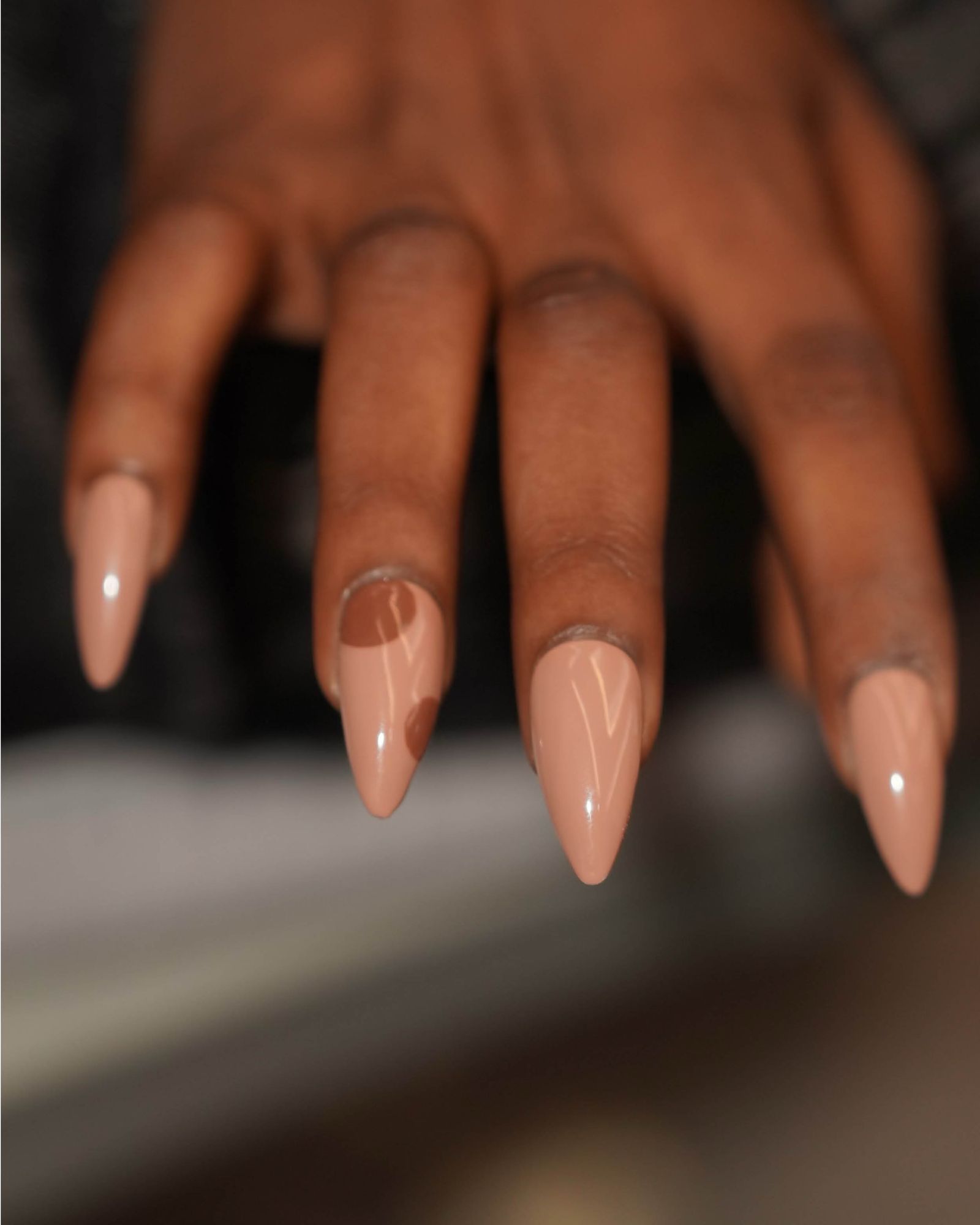 Sharp acrylic nails in glossy nude with two large brown polka dots.