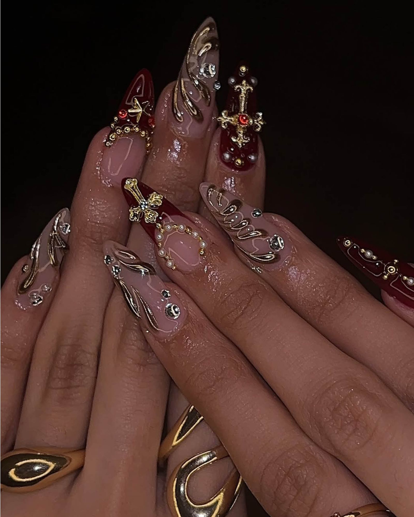 Maroon and nude glossy nails with gold and silver puffy crosses.